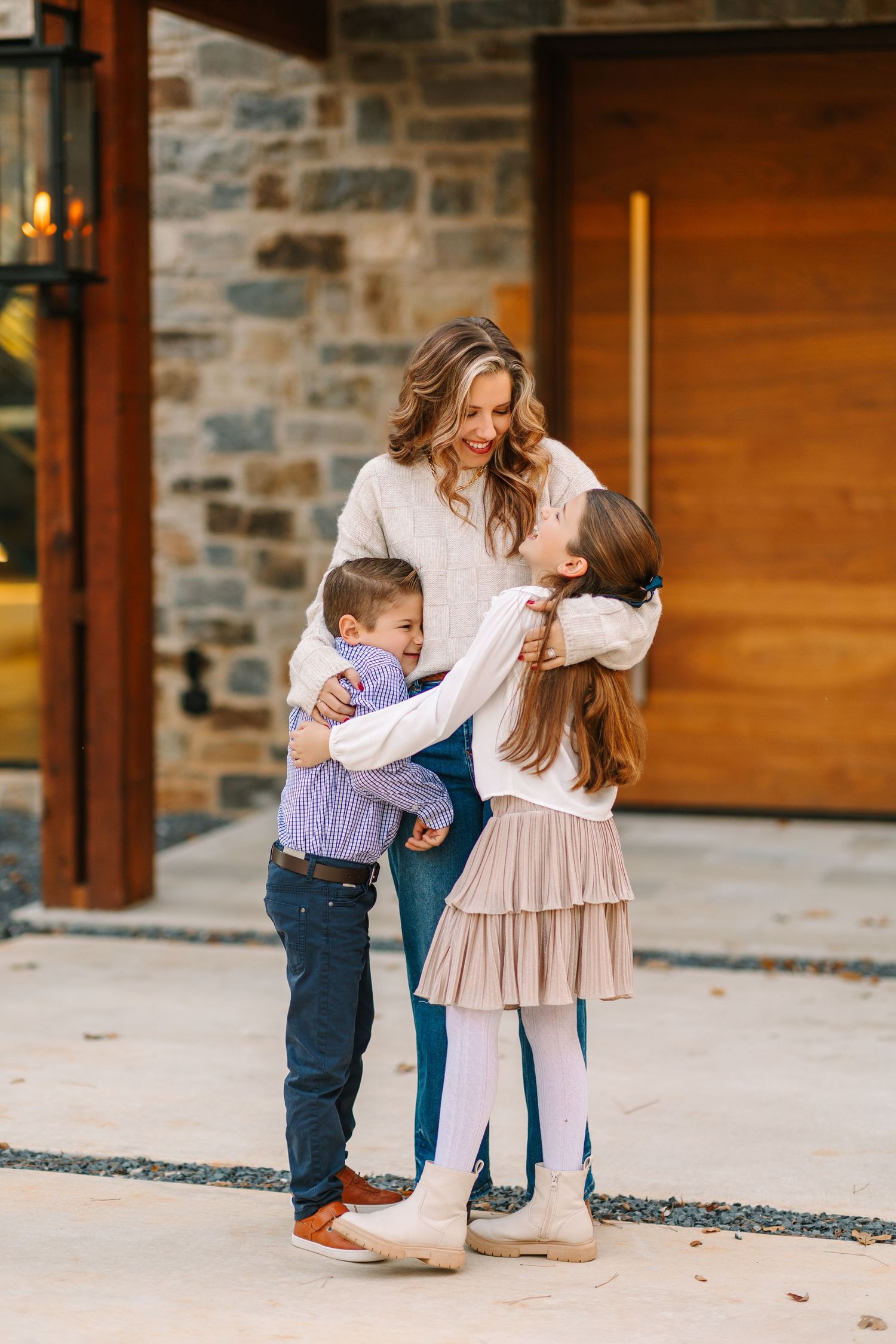 A tender family moment captured outside a modern stone and wood home entrance.