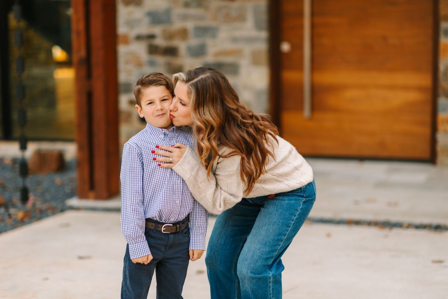 Two people share a sweet moment together outside building with wooden door and stone wall.