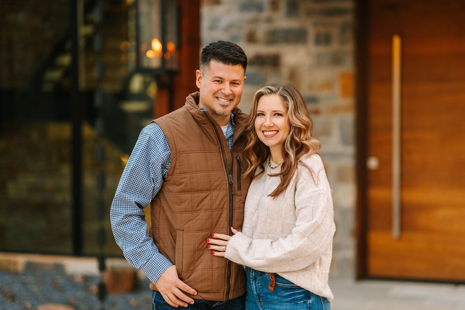An affectionate couple sharing loving moments in front of a rustic stone building facade.