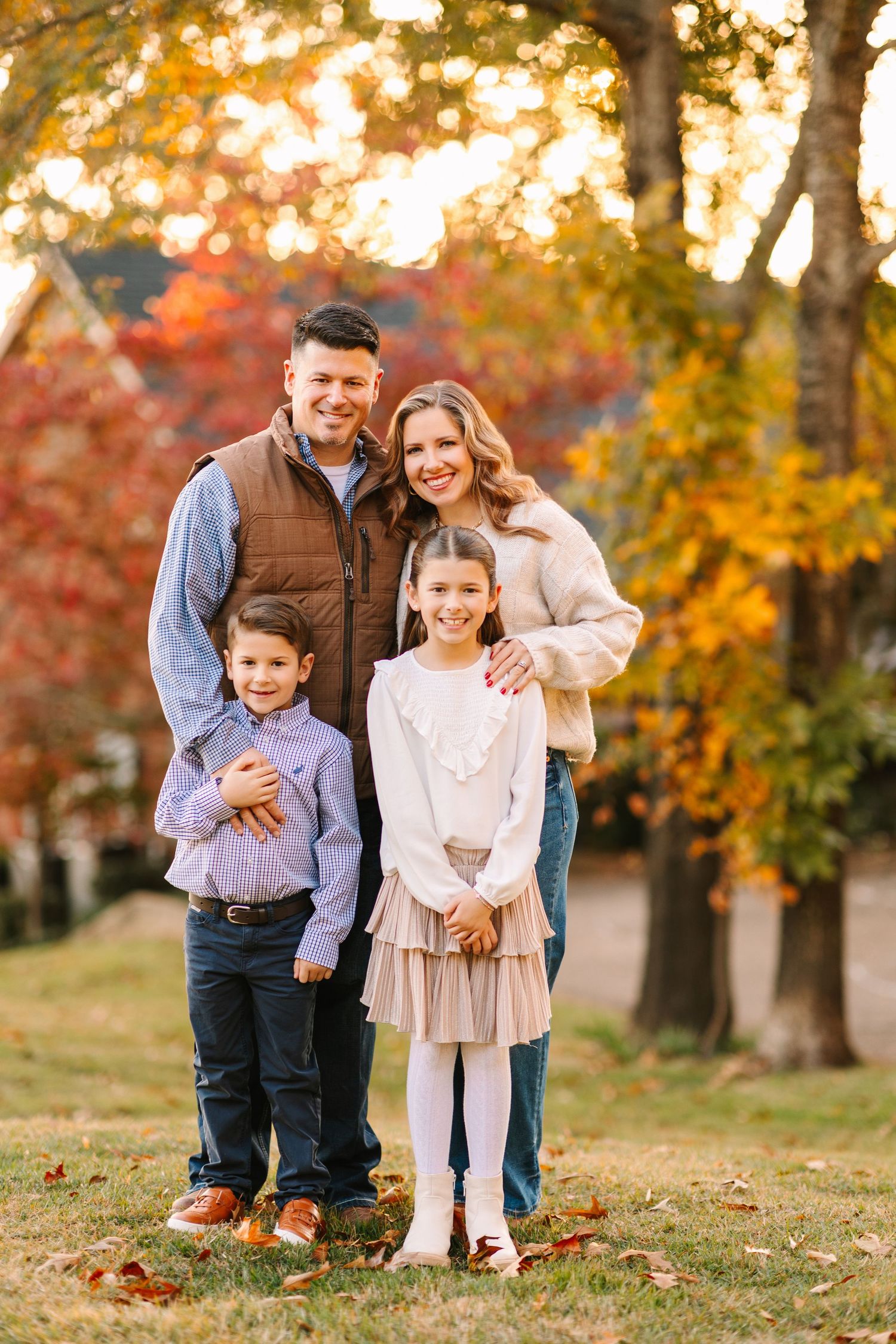 Family enjoying a warm autumn afternoon in a park with golden foliage and fallen leaves.