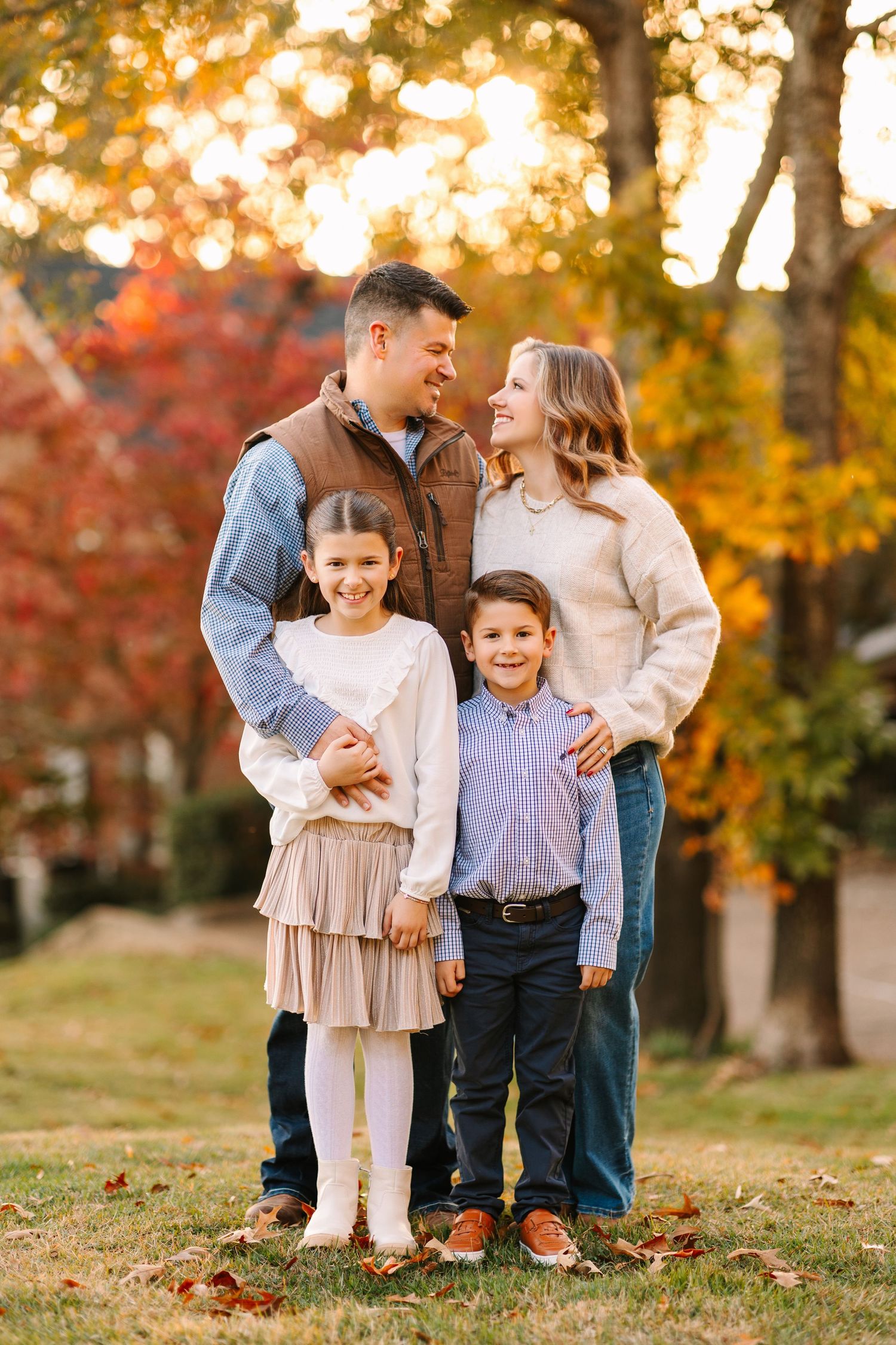 A happy family shares joyful moments together outdoors during autumn with golden foliage and red leaves in the background.