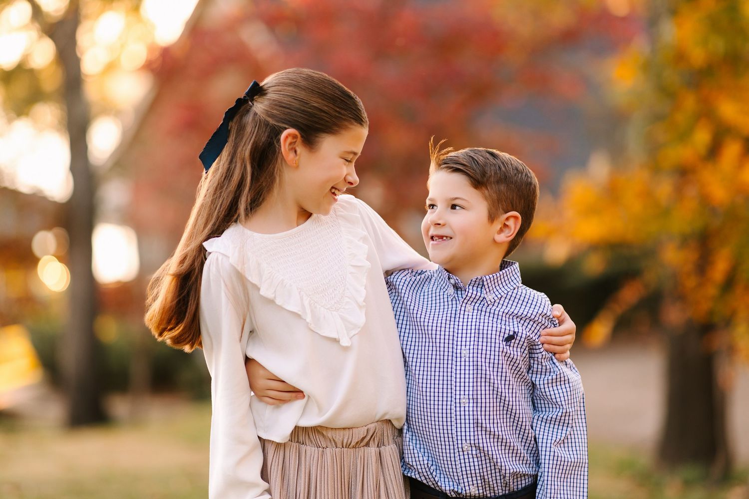 Family members pose together in front of autumn foliage during outdoor sunset portrait session.