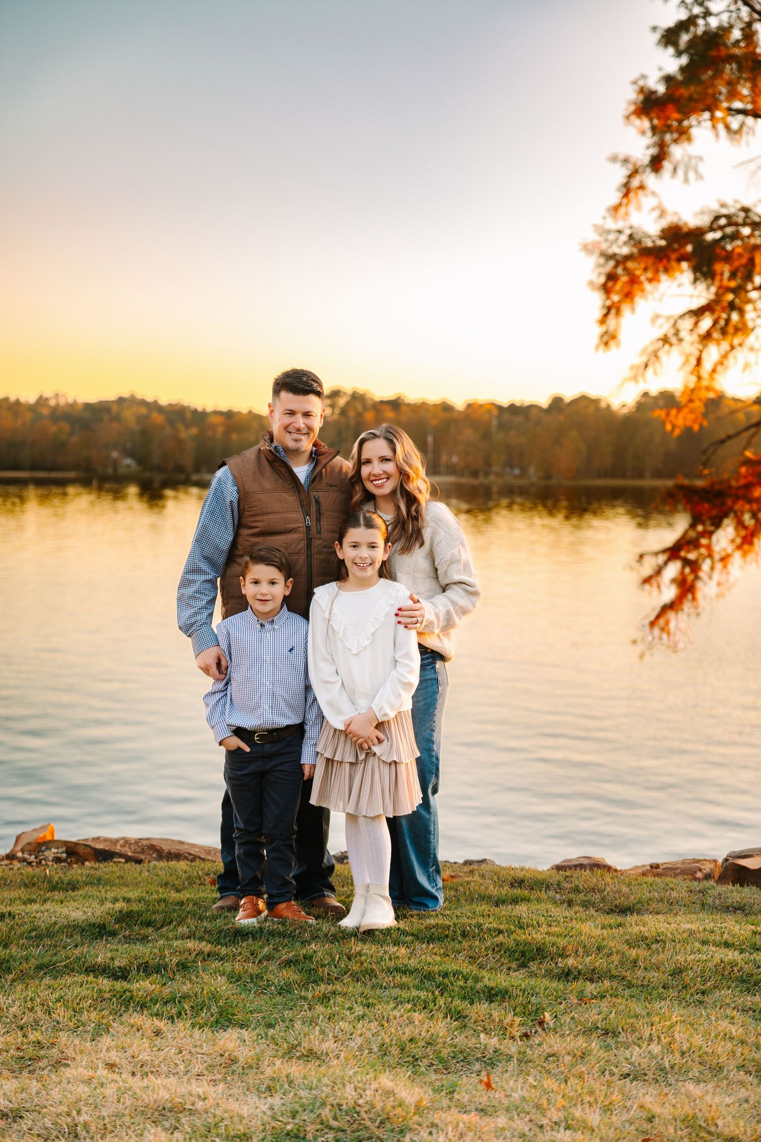 A group enjoying a golden sunset by a serene lake, with autumn trees creating a warm, peaceful atmosphere.