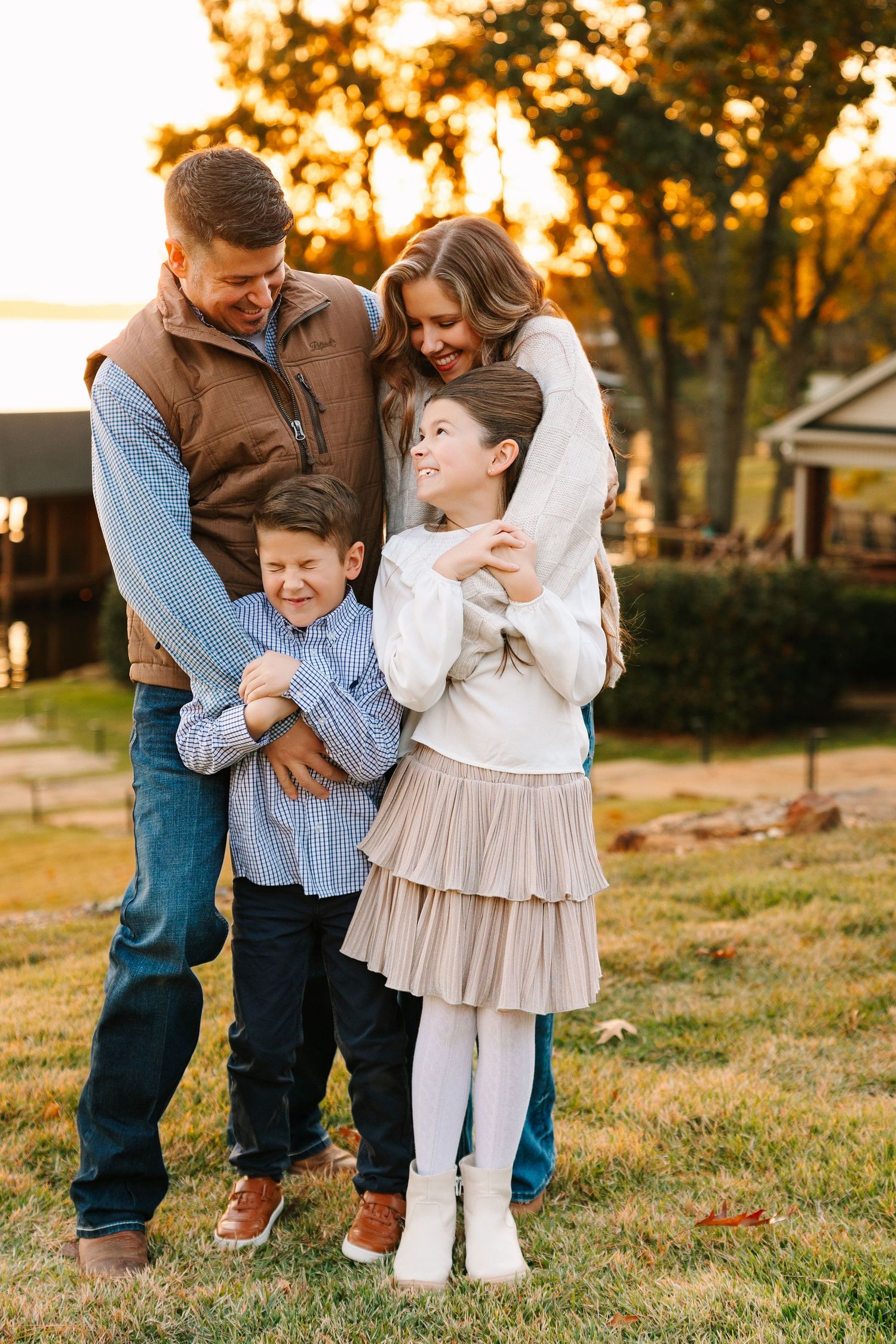Family shares tender moments together in a golden sunset setting on grassy field.