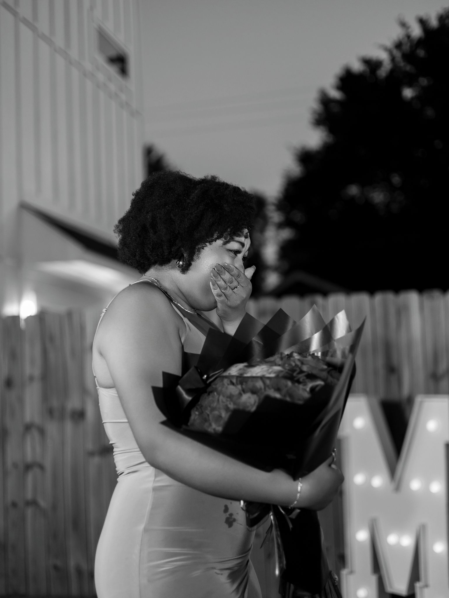 A couple shares a romantic dance together under twinkling string lights at an outdoor event.