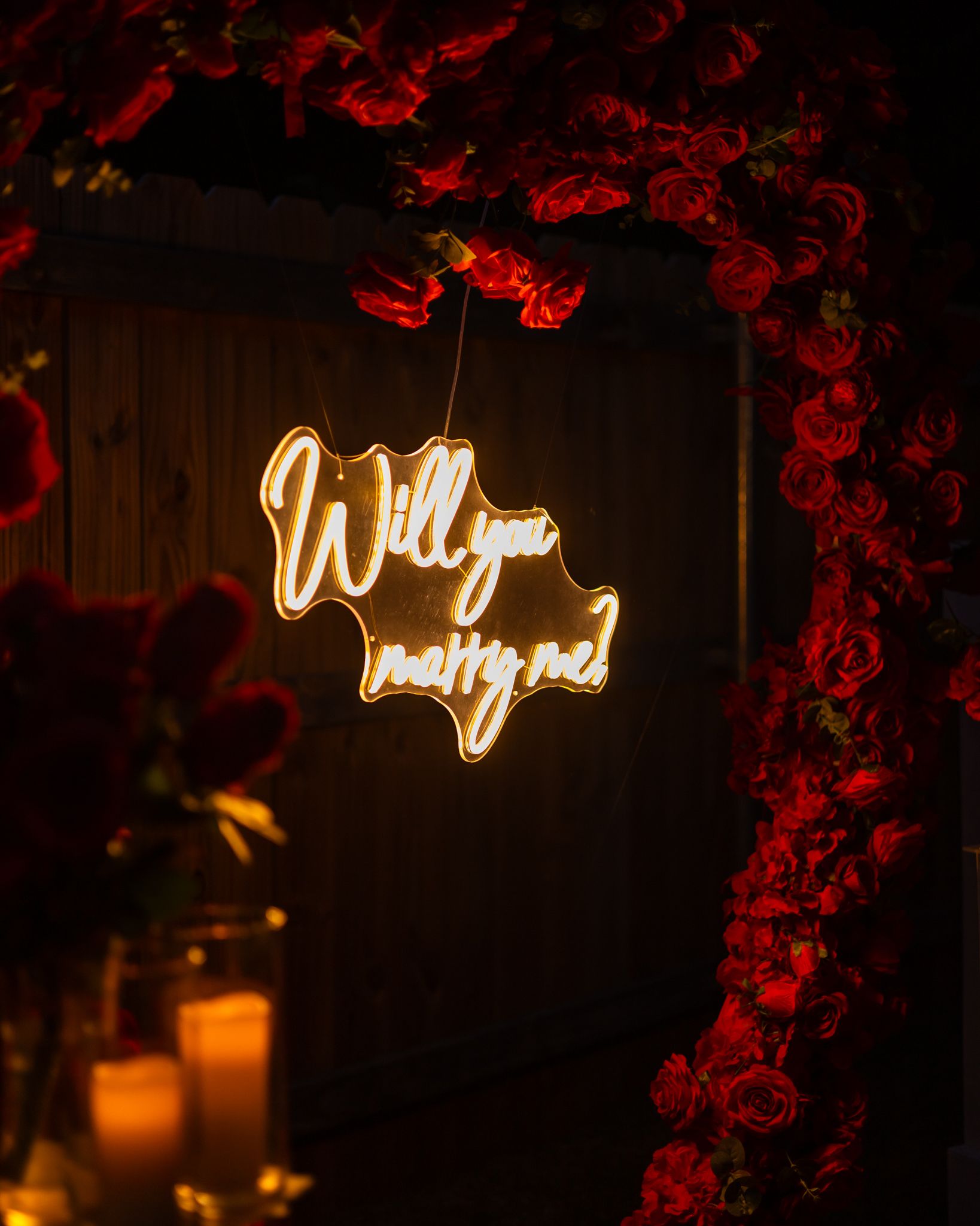 Illuminated cursive neon signs glowing warmly against a dark background with red floral accents.
