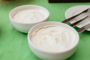 White creamy sauce or dip served in small round bowls on a green surface.