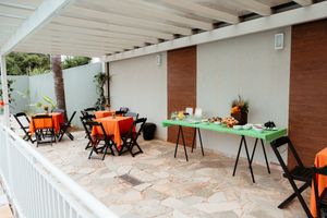 White covered outdoor patio area with folding chairs and tables set up for an event.