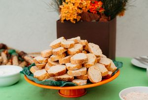 Homemade coconut macaroons arranged on orange plates at a party table setting with drinks and decorations.