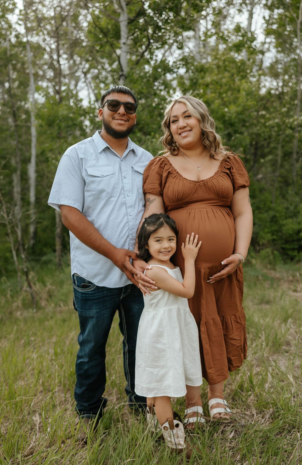 Family maternity photoshoot in a natural outdoor setting with birch trees.