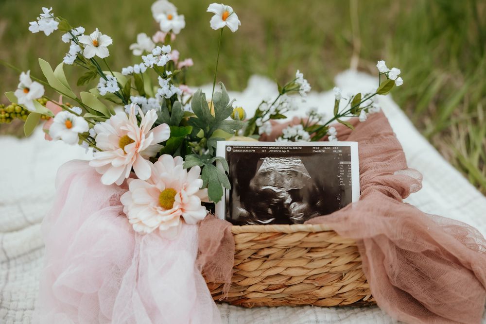 Delicate white flowers and a sonogram photo displayed in a rustic outdoor setting.