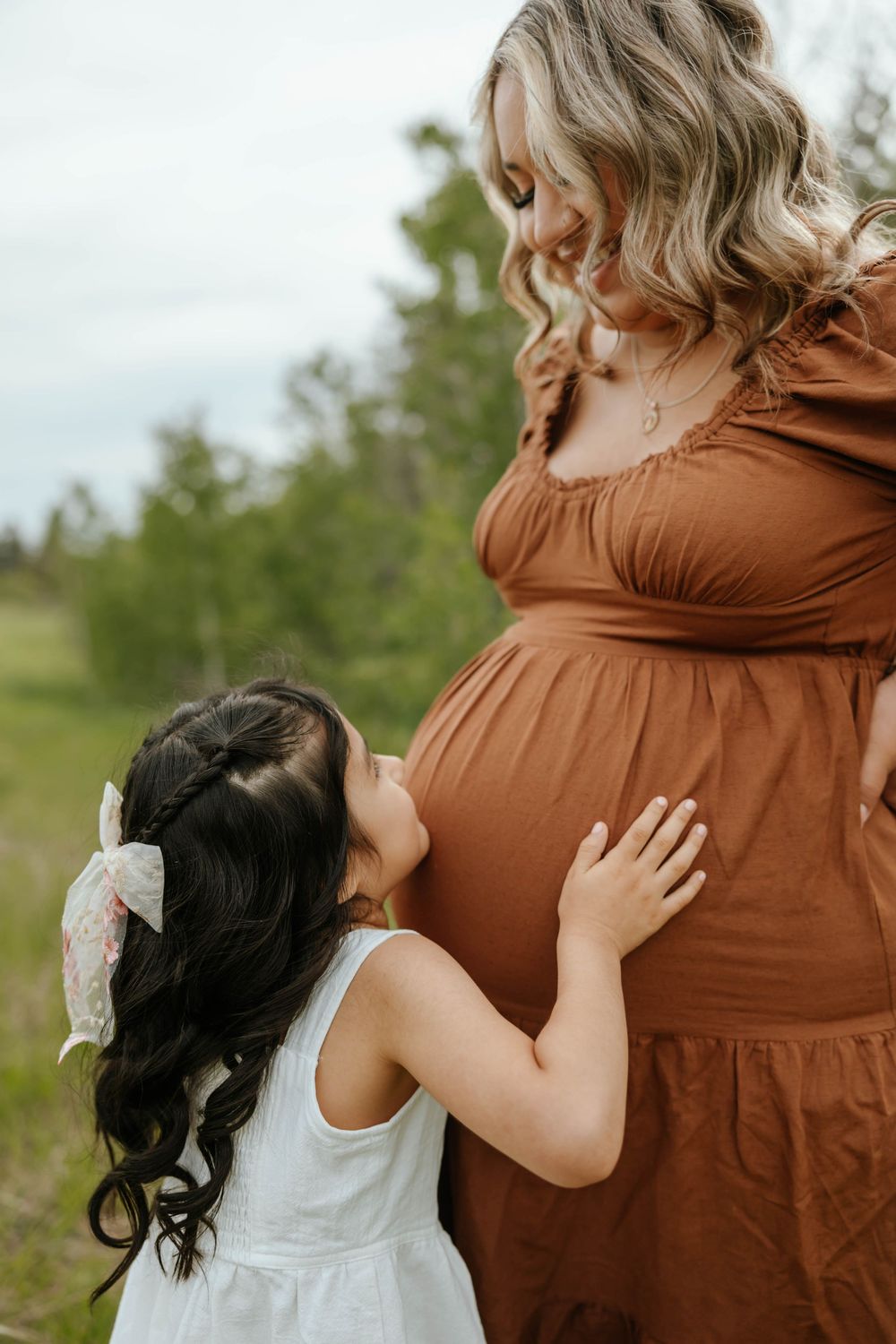Sweet family moment captured during maternity photoshoot in nature.