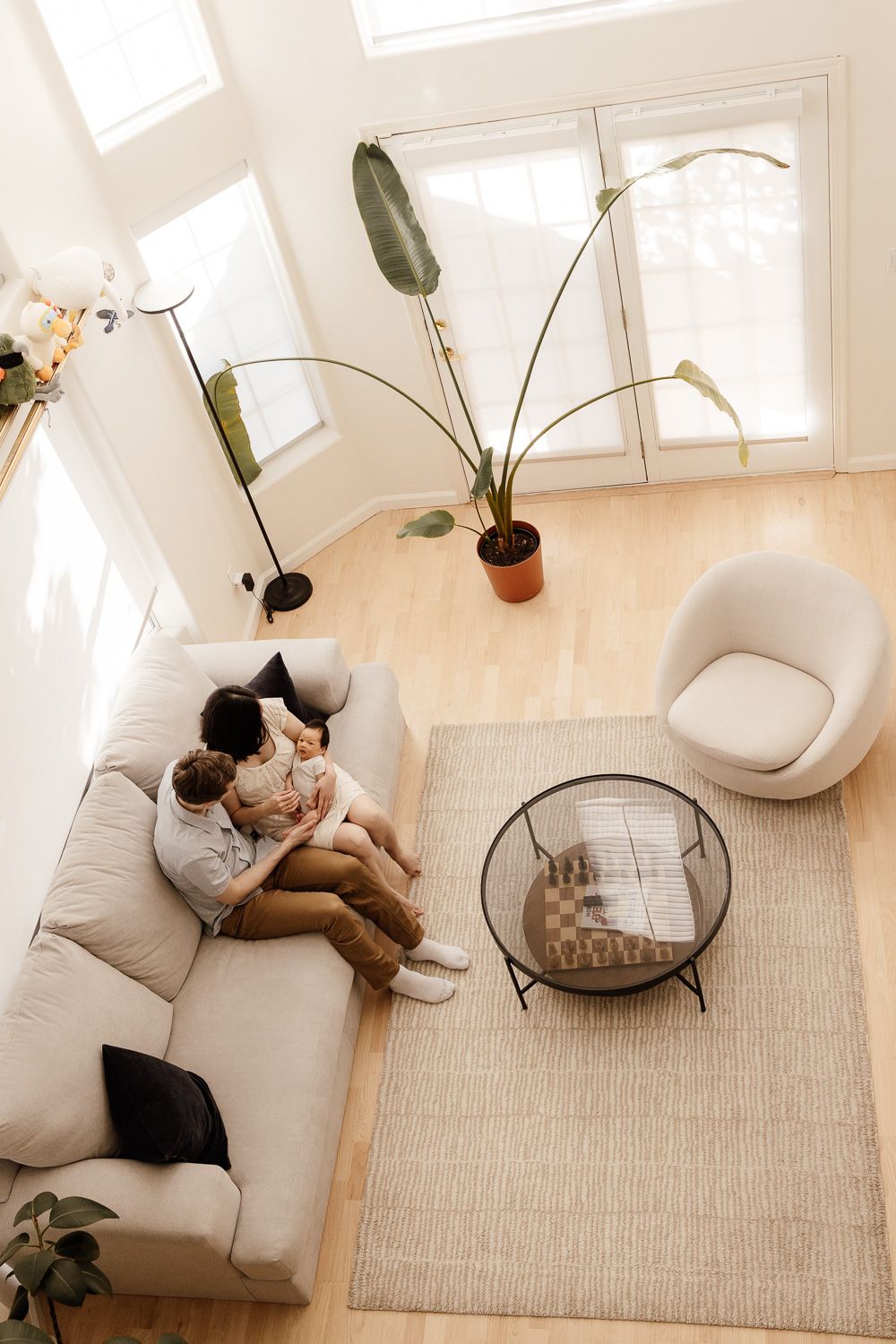 Parents cuddle their newborn baby at their photo session with Cindy Tucey Photography who photographs them from above their living room