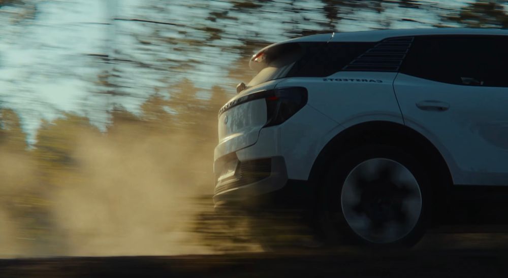 Motion blur of car driving past trees with sunlight filtering through.