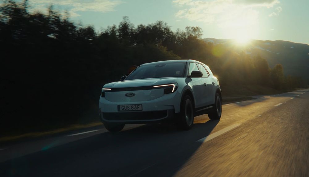 White sports car driving on winding road during golden hour.