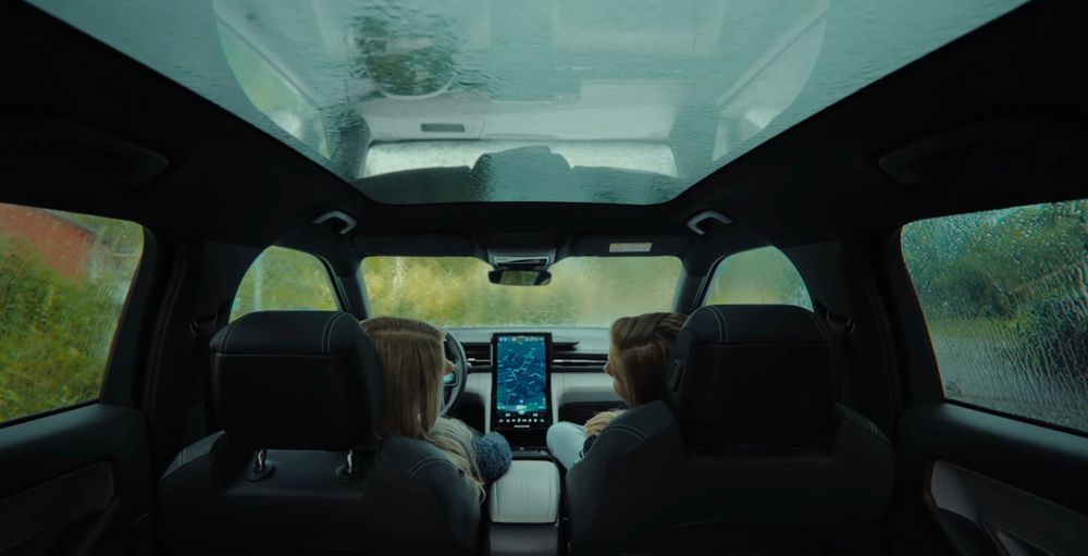 Interior view of car dashboard and windshield while driving through mountainous terrain.