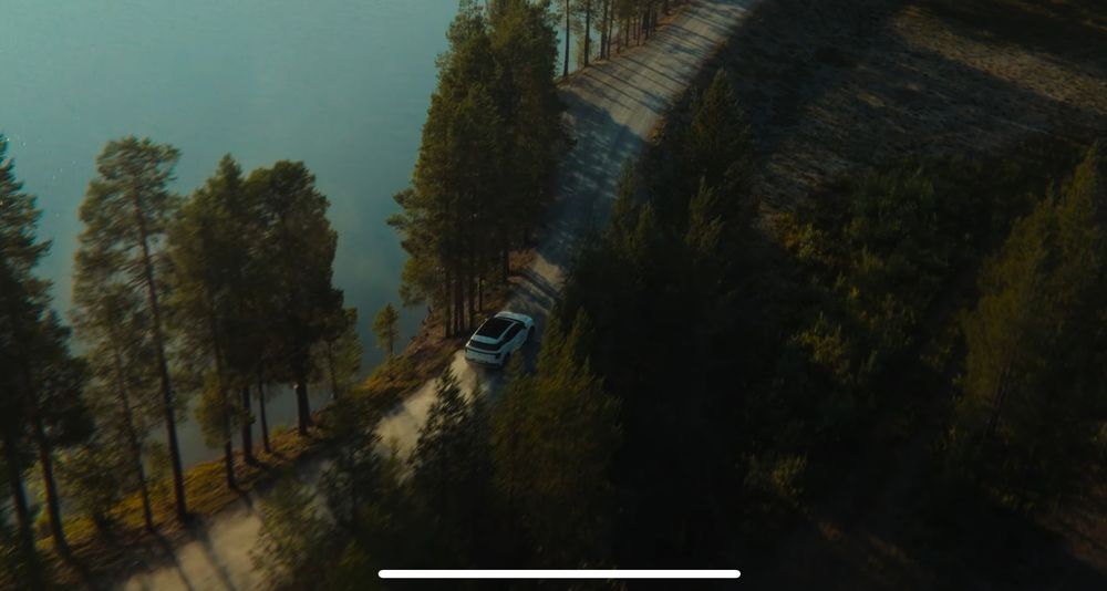 Scenic mountain road winding through a forest with golden sunlight filtering through the trees.