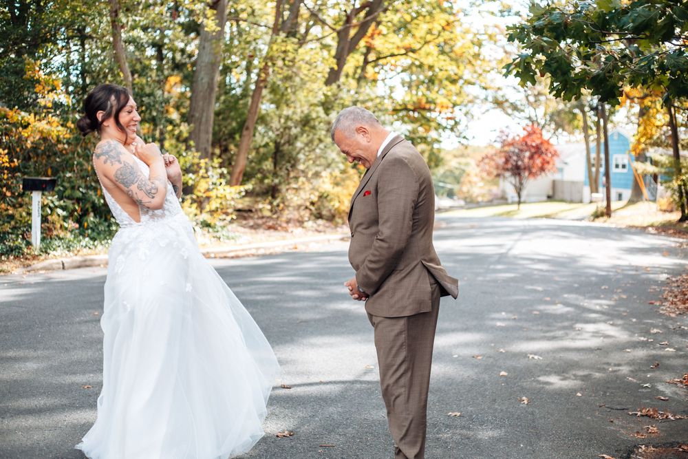 Autumn wedding scene on a tree-lined path with fallen leaves creating a romantic outdoor setting.