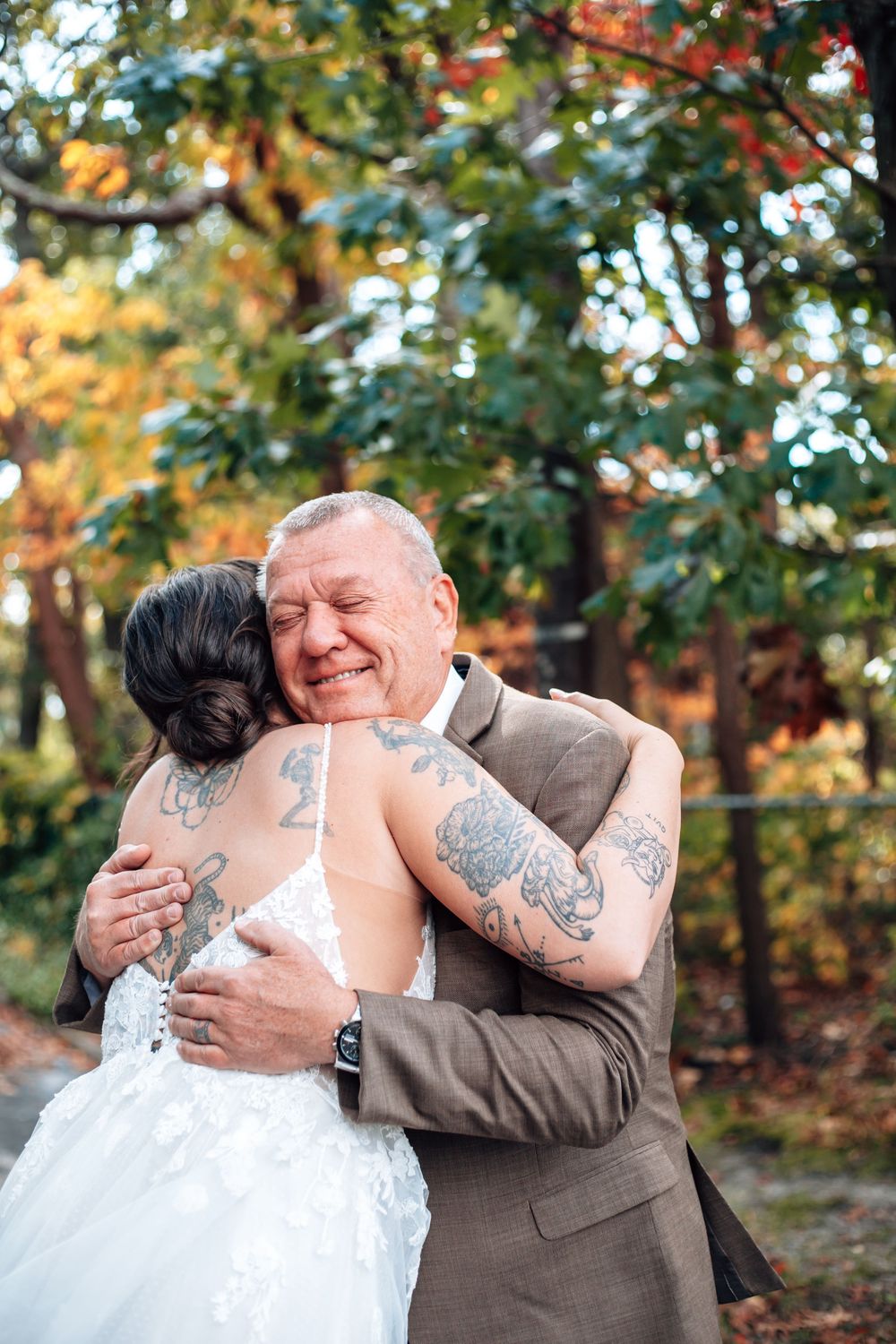 Couple shares emotional first look moment in outdoor autumn setting with golden leaves.