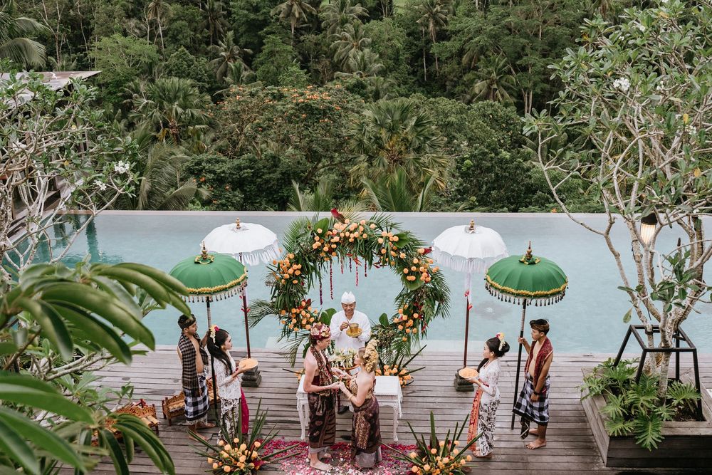Elegant outdoor wedding venue decorated with floral arrangements and green parasols.