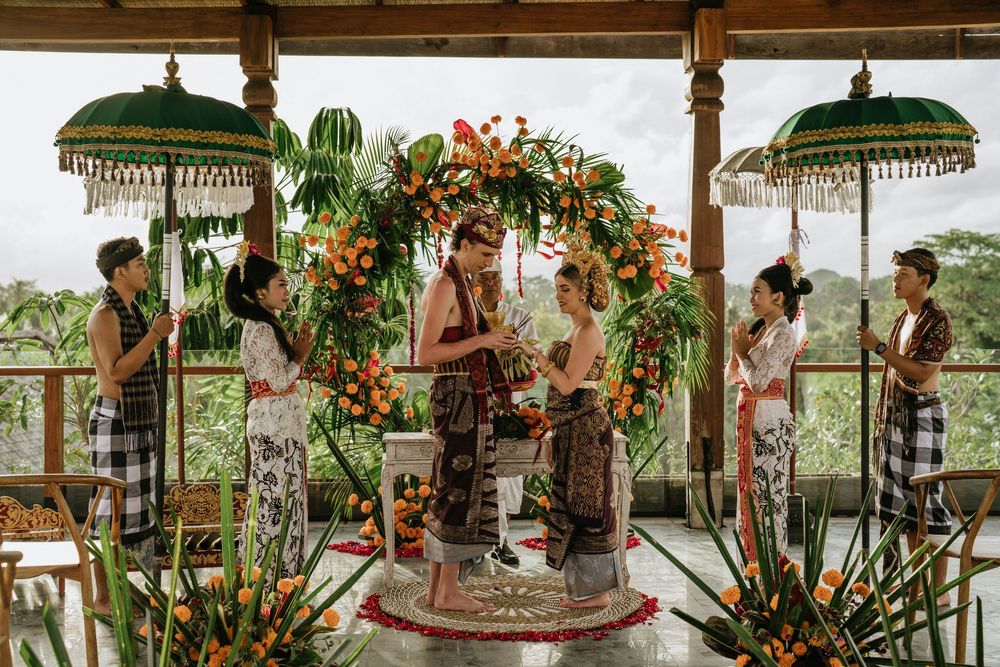 Wedding ceremony procession under green umbrellas with tropical floral decorations.