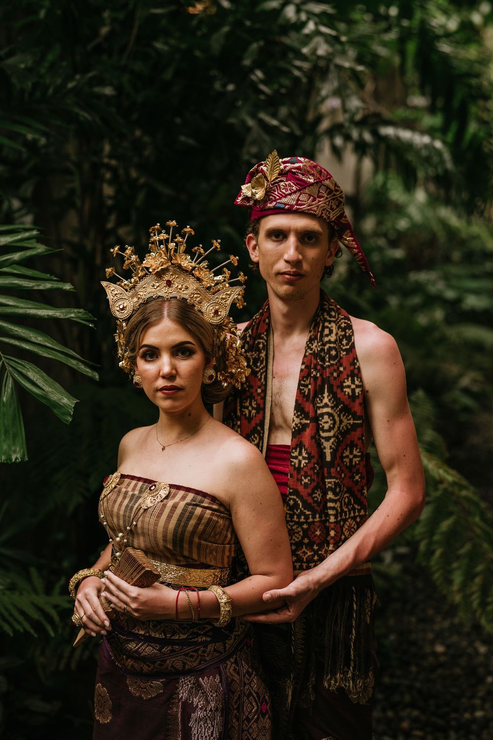 Artistic portrait session in a tropical forest setting with ornate costumes and gold crowns.