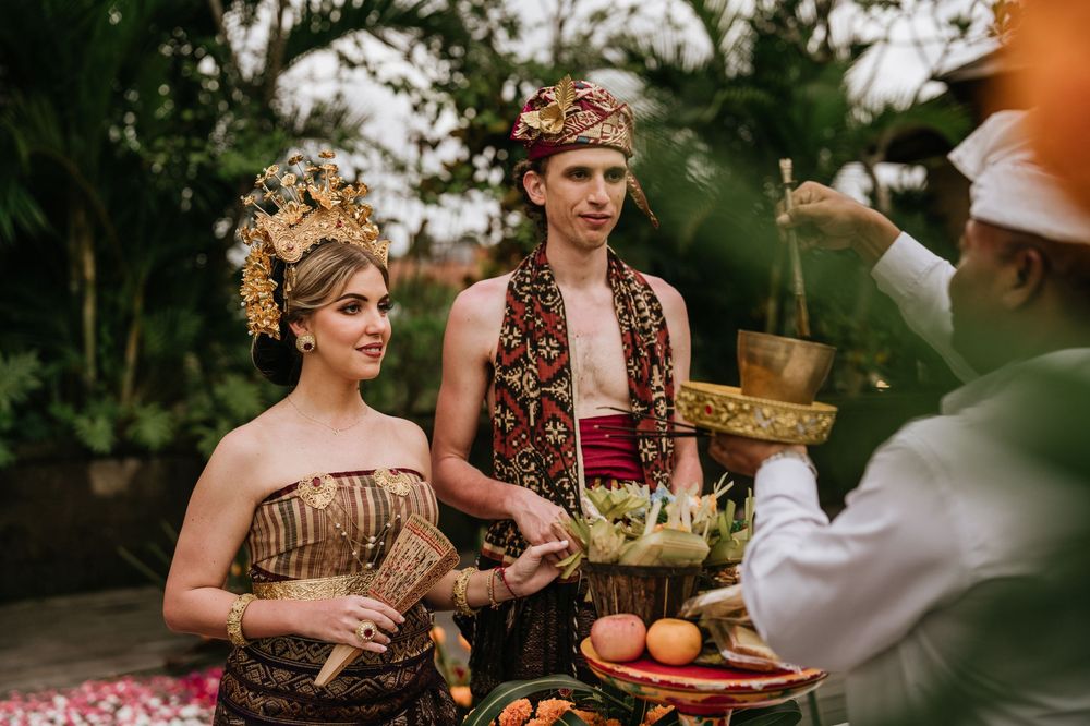 Traditional ceremony with ornate costumes and decorative offerings in a tropical setting.