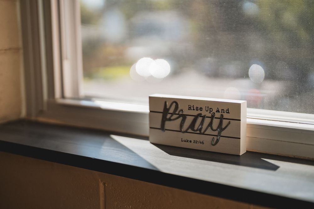 A collection of wooden signs and lettering decorations displayed along a window sill in soft natural light.