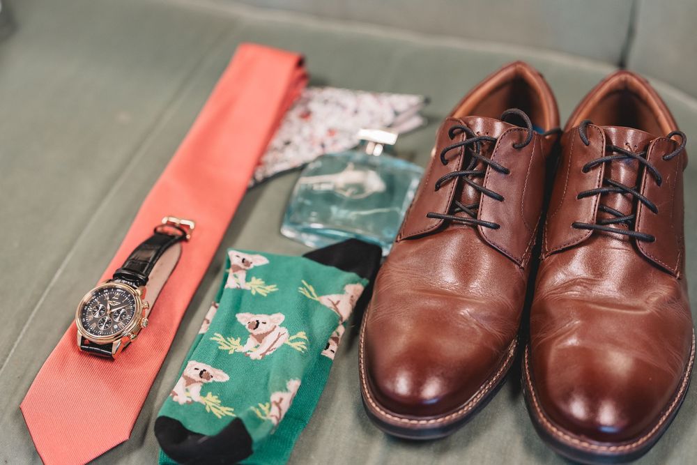Four photos showing brown leather dress shoes being polished and shined on a wooden surface.