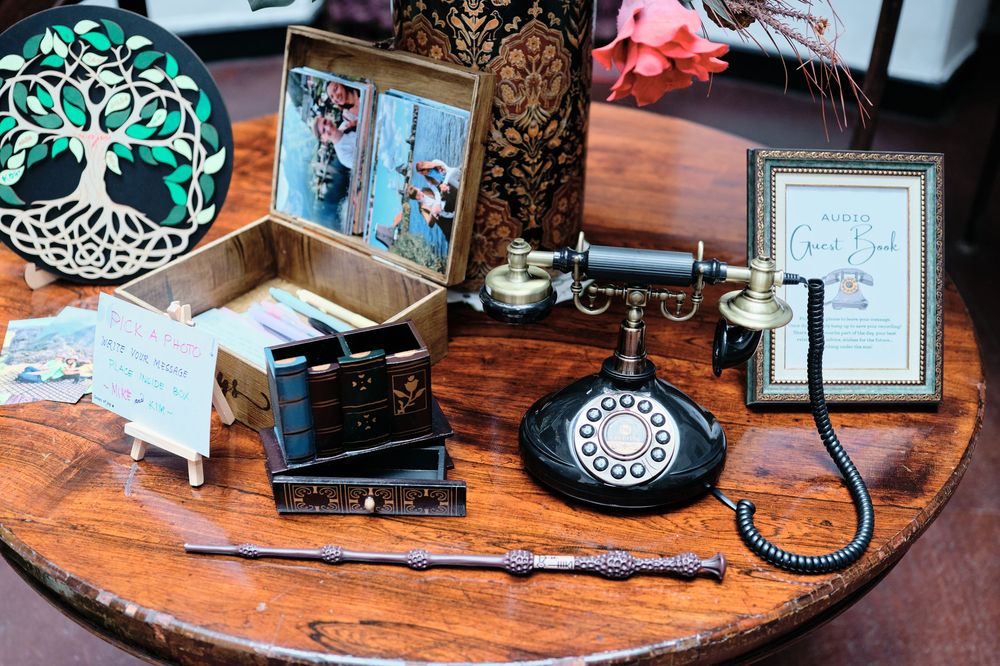 A rustic wooden table displays vintage telephones, antique decor items, and framed artwork in a nostalgic arrangement.