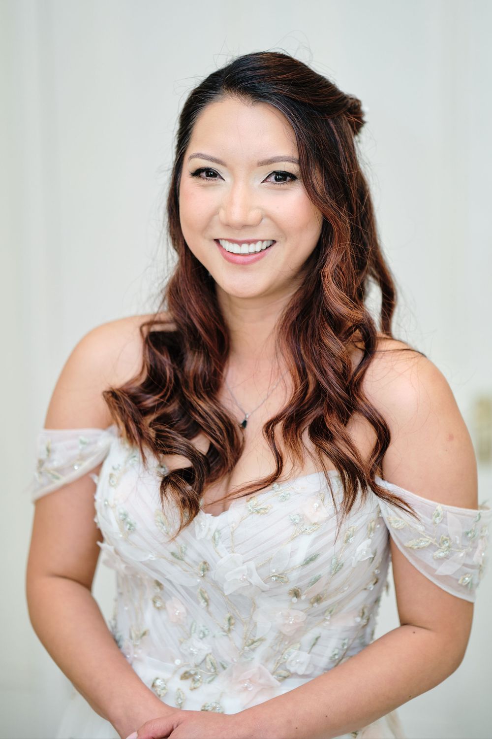 A bride wearing an elegant off-shoulder white floral wedding dress smiles warmly in a series of portrait shots.