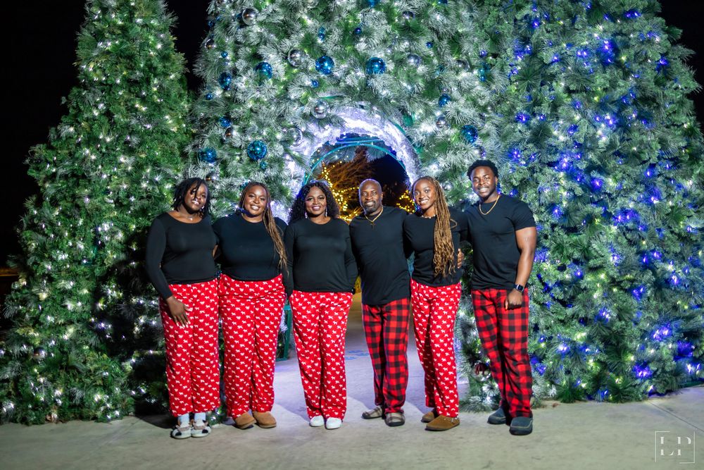 Group photo with people wearing black tops and red plaid pants against a floral backdrop.