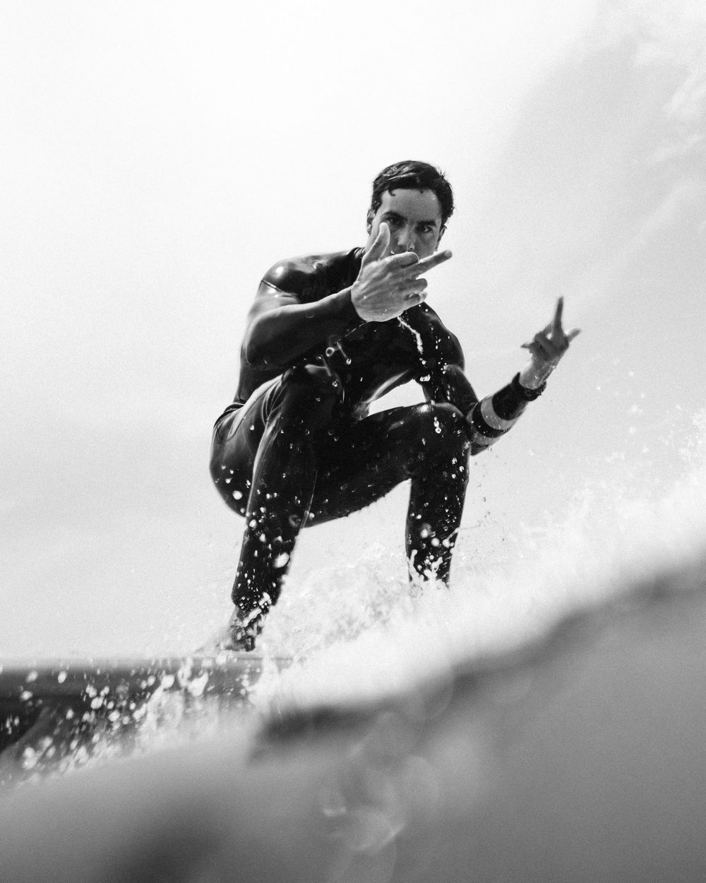 A black and white surfing sequence shows a surfer riding through waves in a wetsuit.