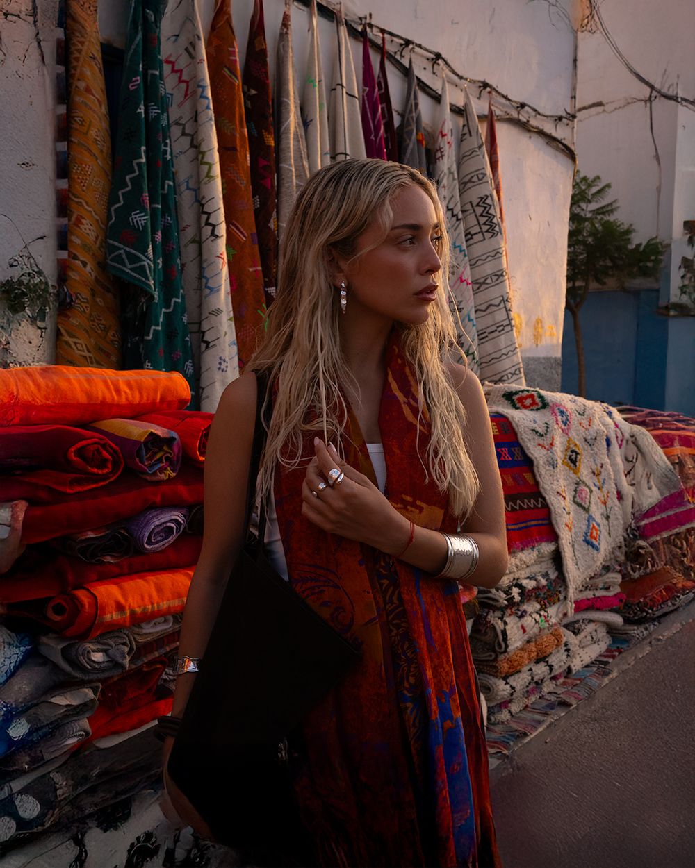 A series of connected photos showing a woman in a brown coat walking past graffiti-covered walls at sunset.