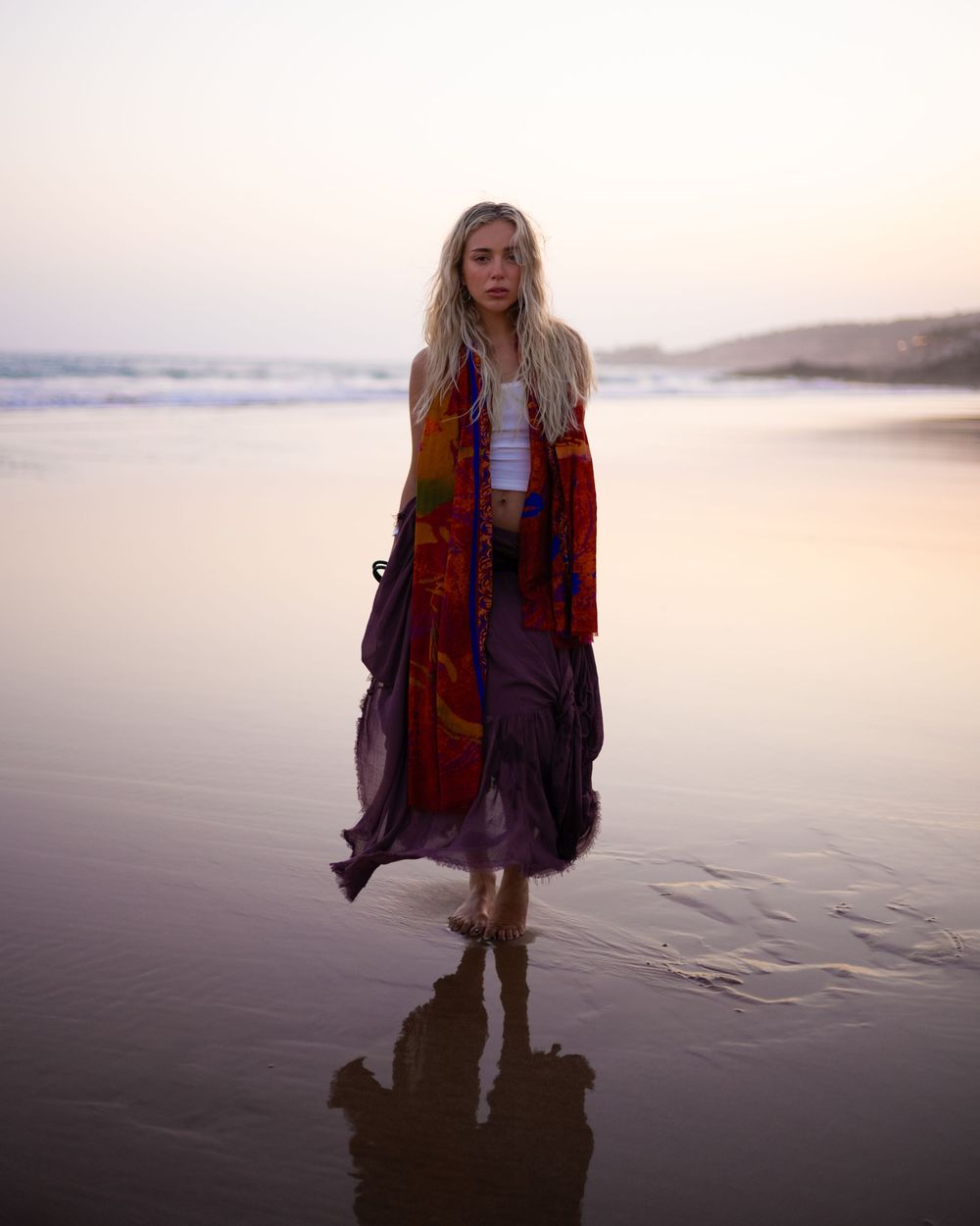 A figure stands silhouetted against a misty sunset on a beach, creating a moody and atmospheric scene.