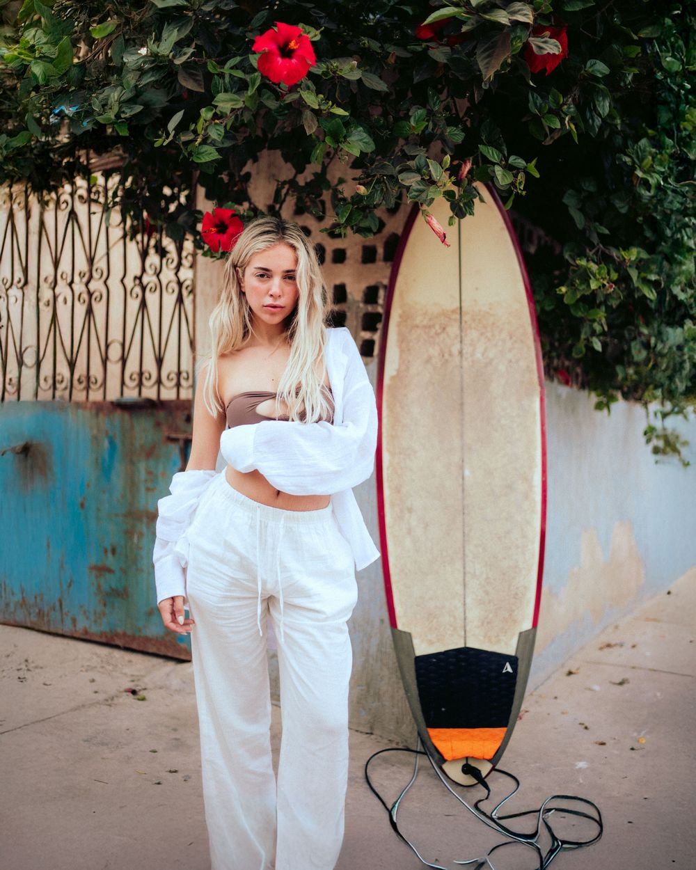 A series of photos showing a white-clad figure posing artistically against a garden wall with red flowers.