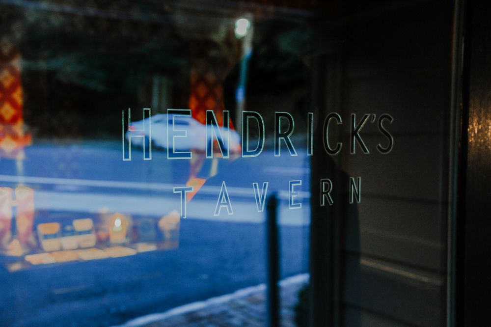 Neon bar signs at night illuminate through glass windows with reflective surfaces.