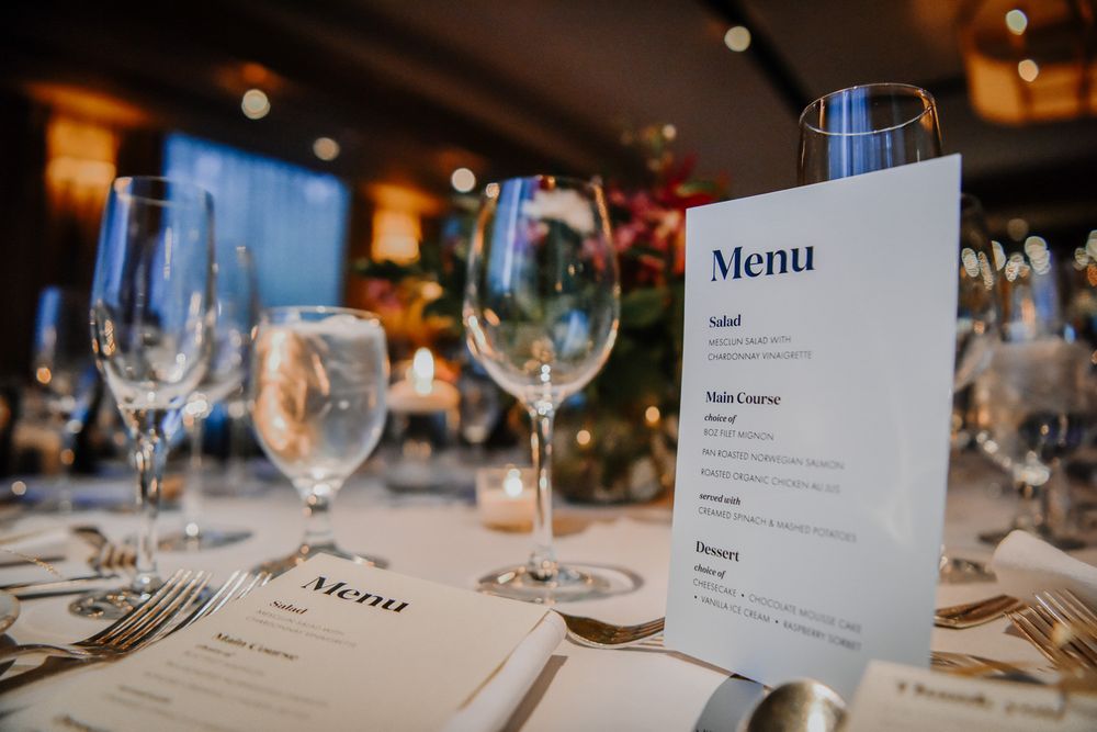 Elegant restaurant table settings with white tablecloths, wine glasses, and menu cards in a dimly lit dining room.