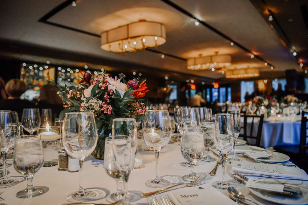 Empty wine glasses are lined up on elegant tables during a formal event setting.