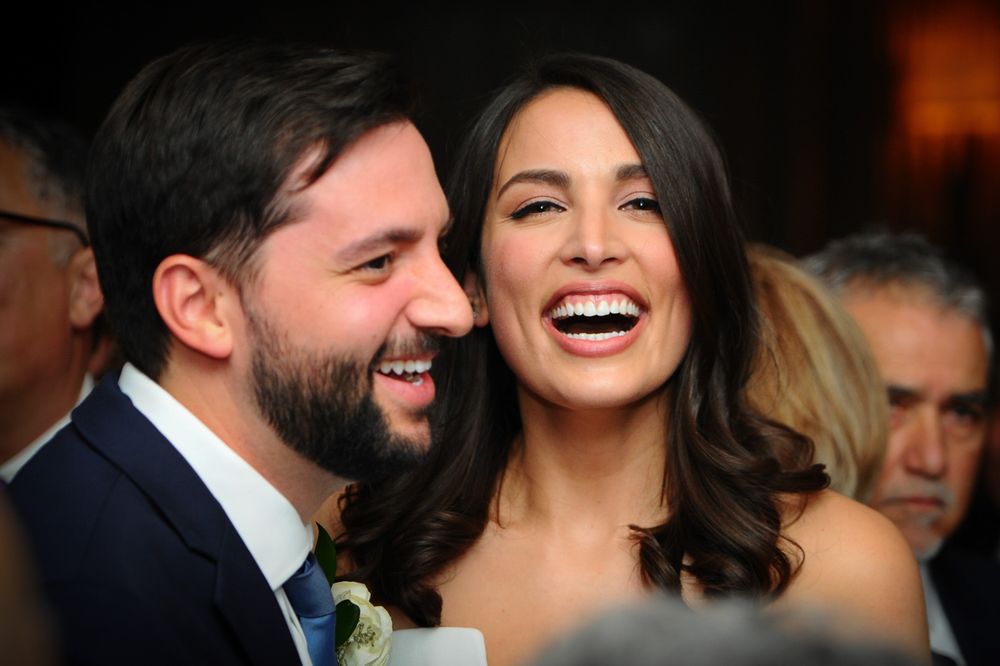 A loving couple shares a candid laughter-filled moment together at an evening event.