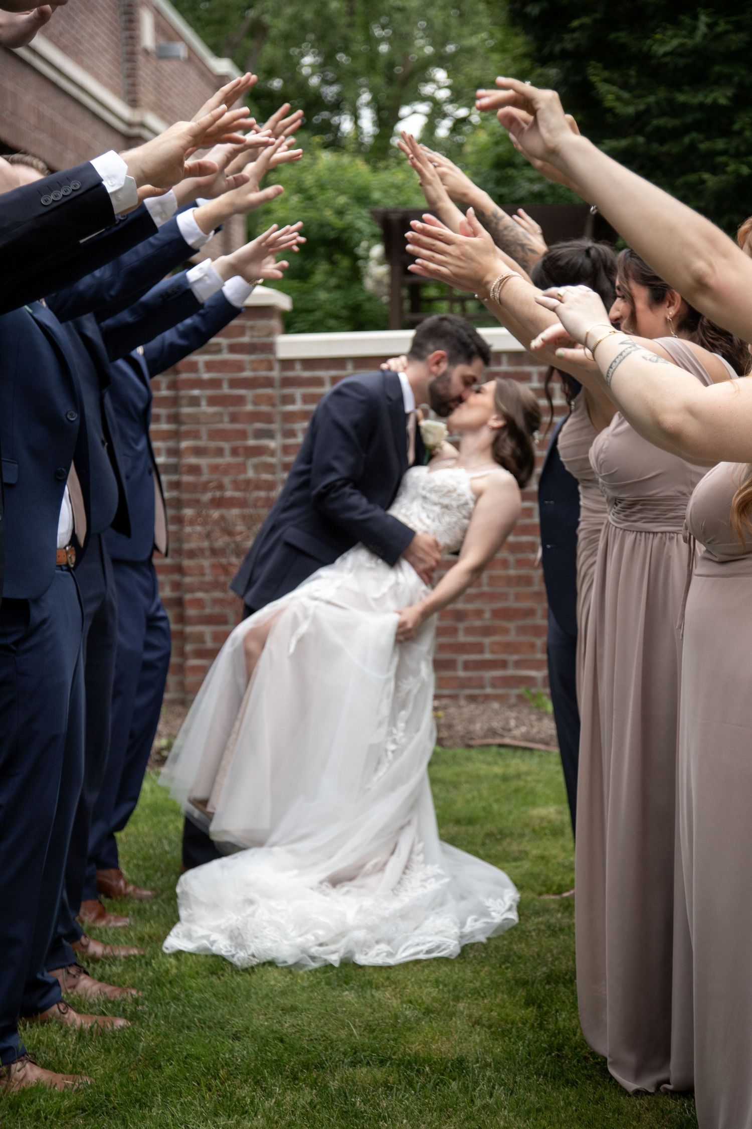 Bride and groom kissing with bridal party making a tunnel Bride and groom in rain at 2gather more wedding venue in michigan