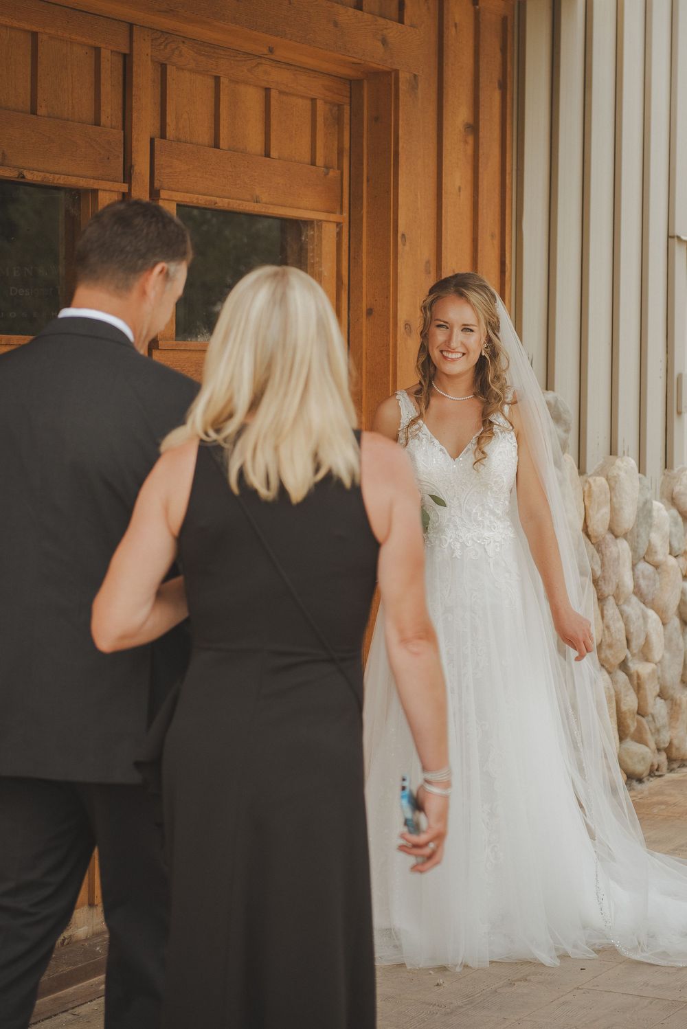 A first look wedding moment captured in a rustic wooden venue with warm lighting.