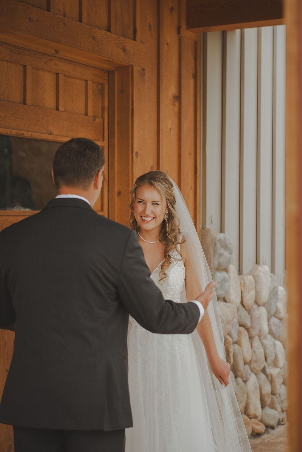 An emotional first look moment between bride and groom at a rustic wooden venue.