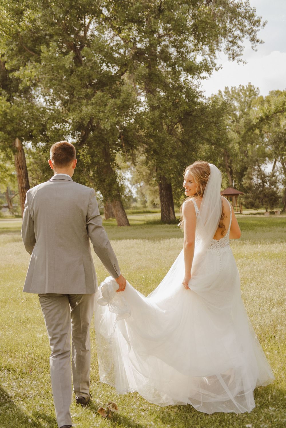 A romantic wedding photo sequence showing a couple walking through a sunlit field with flowing veil and grey suit.