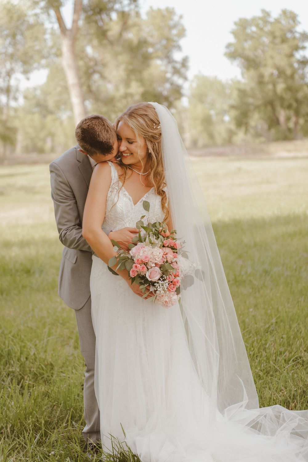 Romantic wedding portraits showing intimate moments in a sunlit field with flowing white dress.