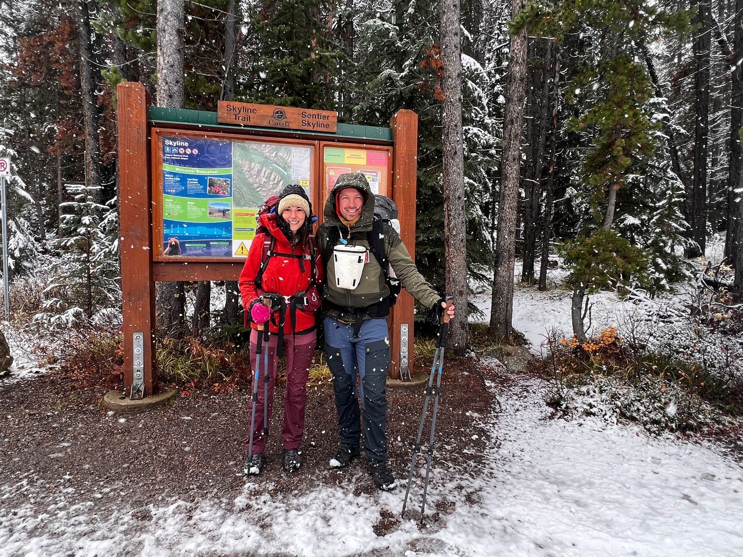Evan Will and Kristen at the Skyline trailhead in snowy forest with hiking poles and backpacks - Jasper National Park