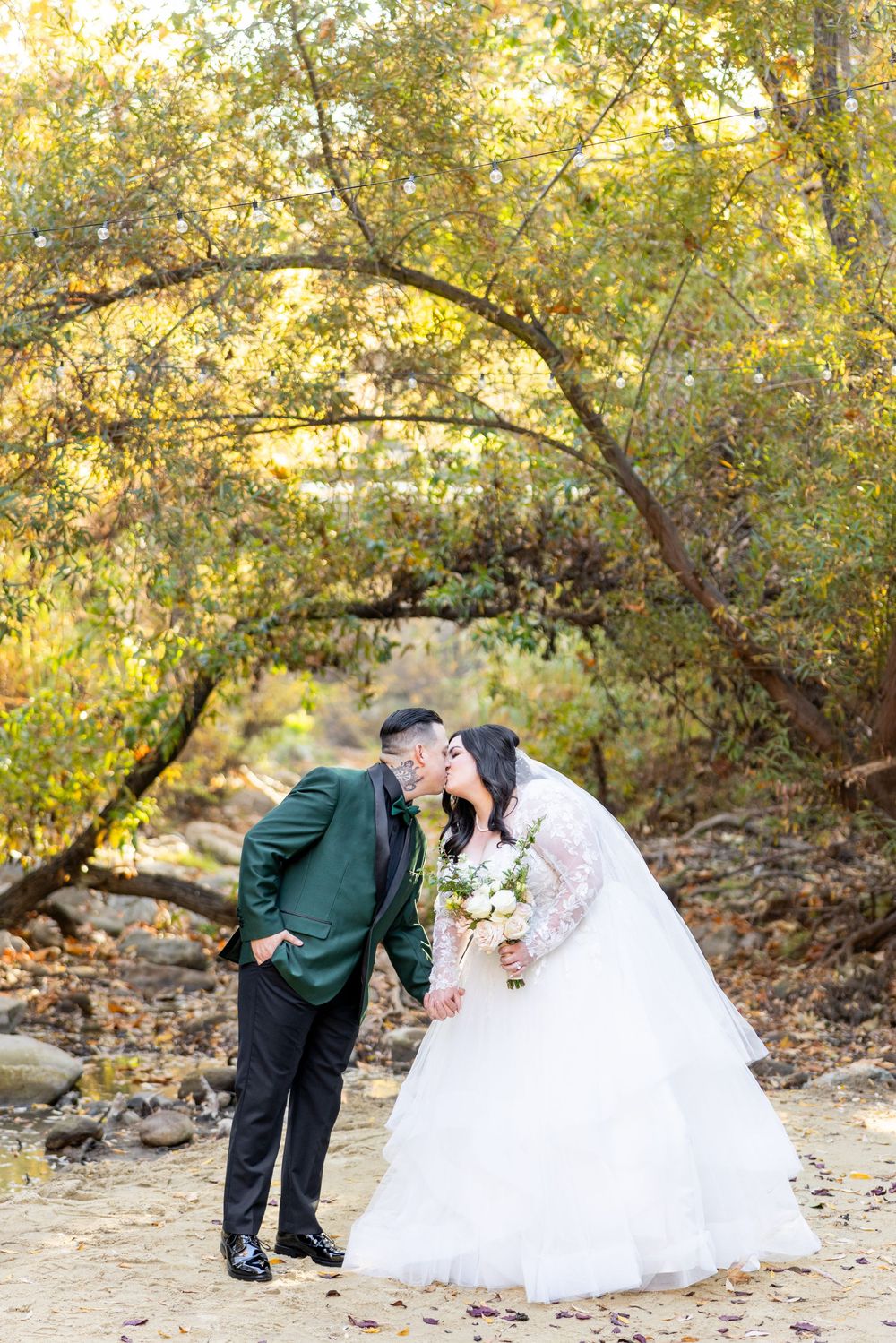A couple in wedding attire shares romantic autumn moments under golden leaves in a scenic outdoor setting.