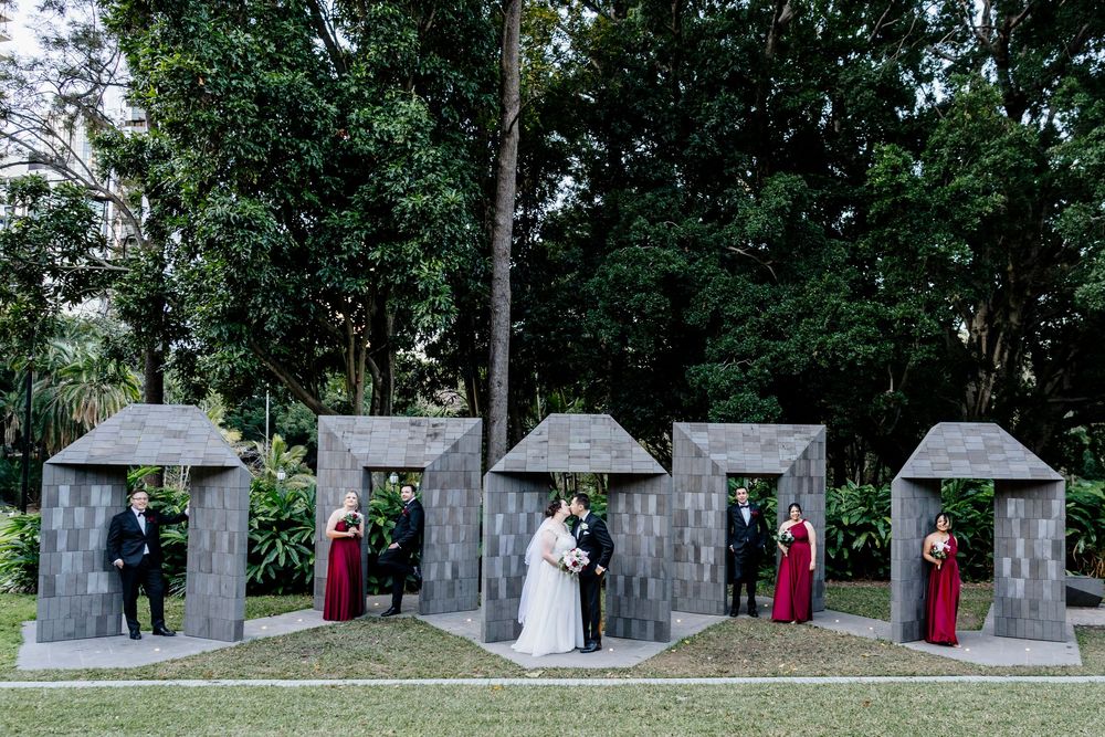 Garden wedding ceremony setup with stone archways and guests in formal attire.