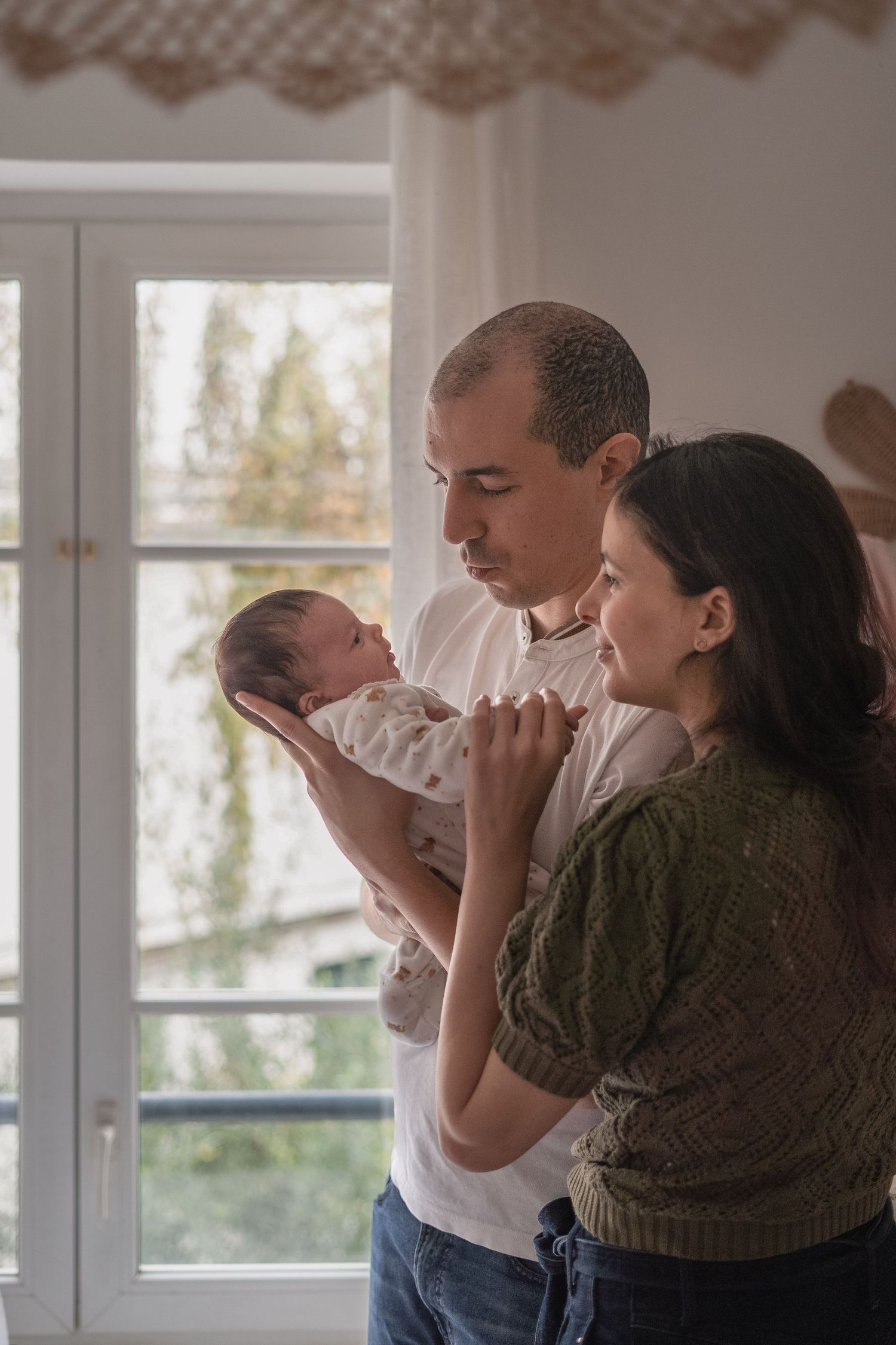 Regards complices des parents devant leur enfant dans sa chambre, à Saint-Germain-En-Laye