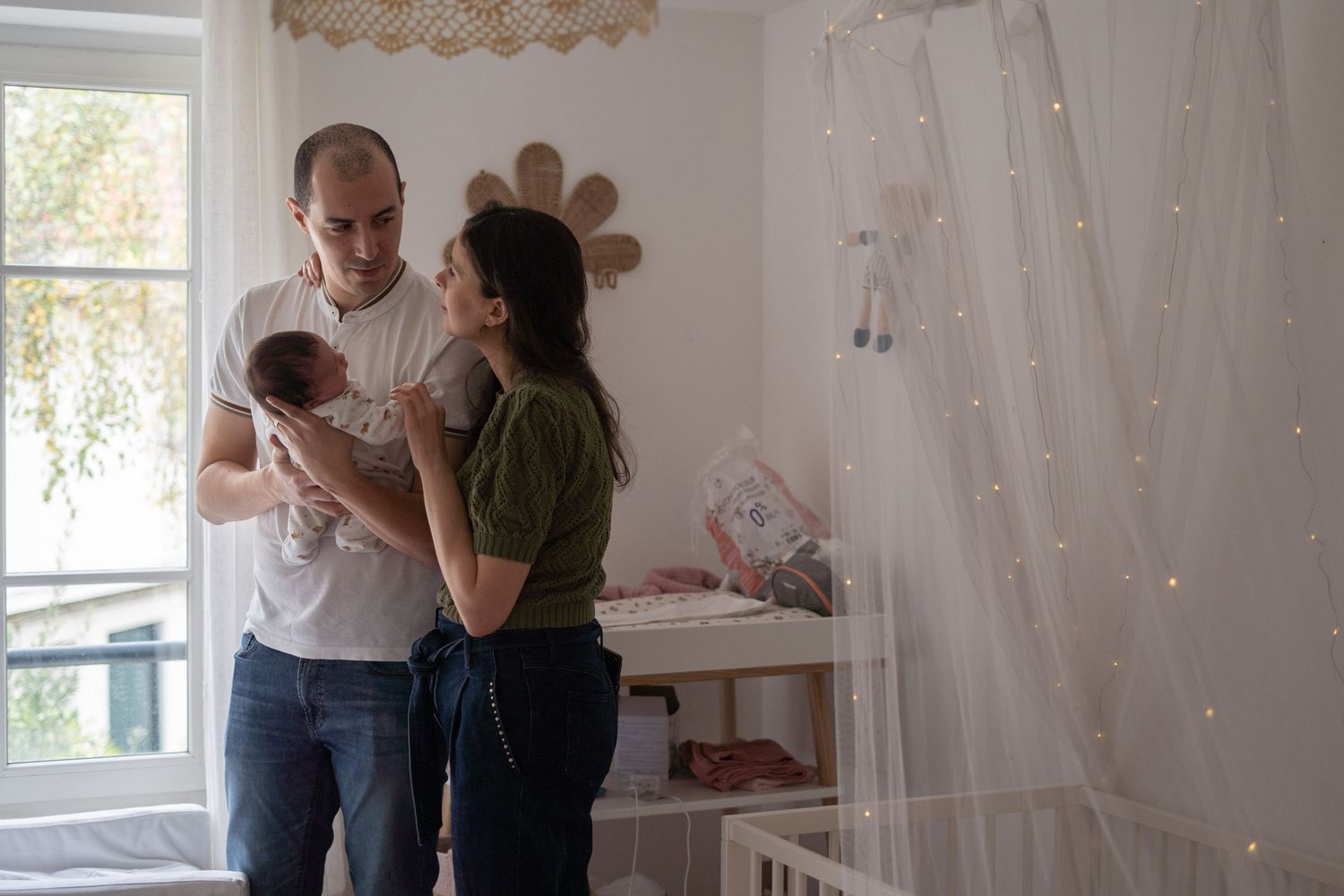 Regards complices des parents devant leur enfant dans sa chambre, à Saint-Germain-En-Laye